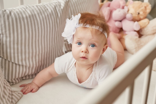 Niña en una cuna con juguetes en la habitación de los niños.