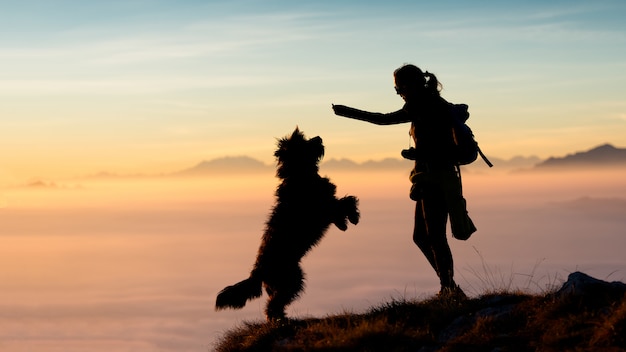 Niña da comida a su perro en las montañas