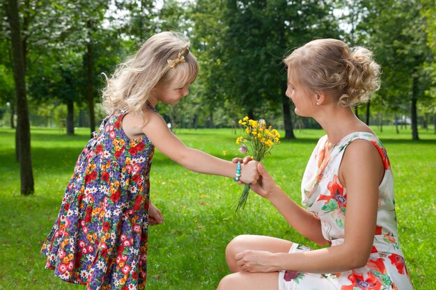 Niña le da flores a una madre