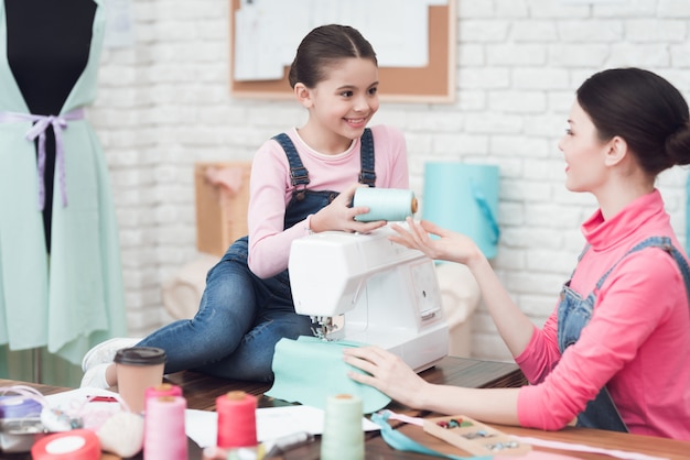 Una niña le da hilos a una mujer.