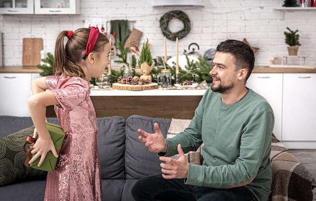 Foto niña le da a papá un regalo navideño festivo