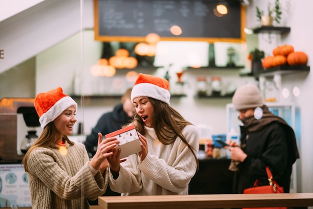 La niña le da un regalo a su amiga en caffe