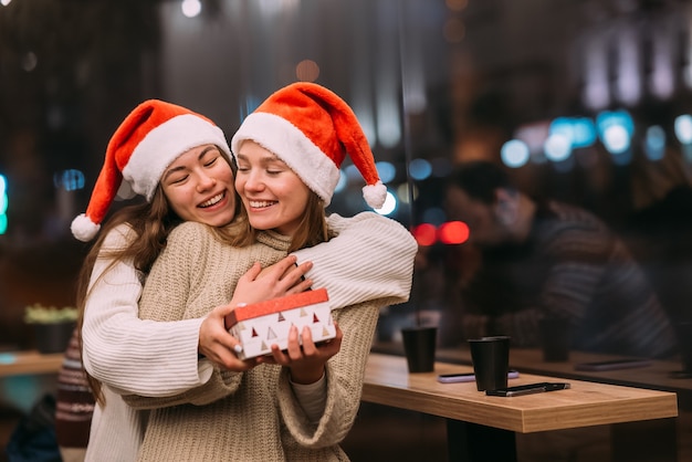 La niña le da un regalo a su amiga en caffe