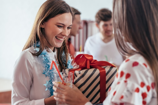 Foto niña le da un regalo a su amiga durante la fiesta de año nuevo.