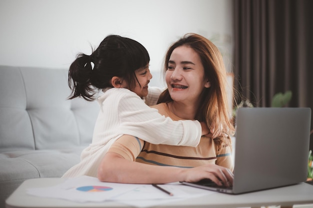 Niña dando un beso a su madre mientras trabaja desde casa