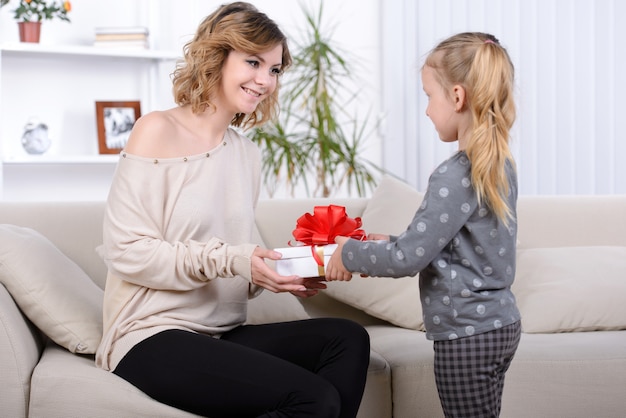 Niña dando un regalo a su madre feliz.