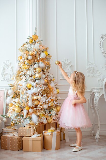 Niña decora el árbol de Navidad en casa