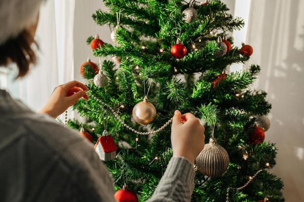 La niña decora el árbol de Navidad para las vacaciones preparándose para la Navidad y el Año Nuevo