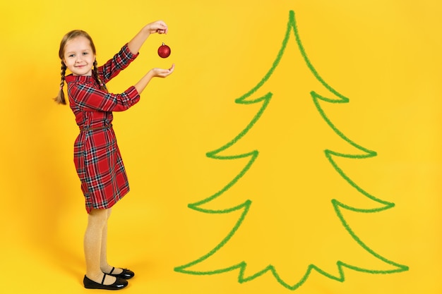 Foto niña decora un árbol de navidad.