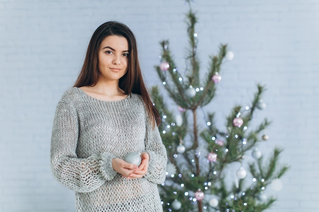 Una niña decora un árbol de Navidad.