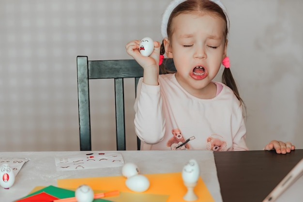 Foto una niña decora huevos blancos con pegatinas con diferentes emociones