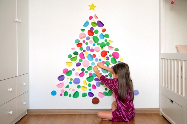 Una niña decora la pared de la guardería para Navidad