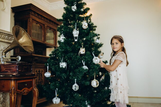 Niña decorando el árbol de navidad con juguetes y adornos Niño lindo preparando el hogar para la celebración de navidad