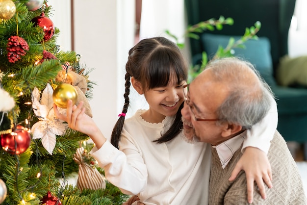 Foto niña decorando un árbol de navidad con su abuelo