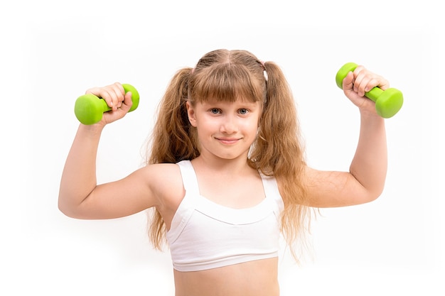 La niña se dedica a la aptitud, deportes con pesas verdes.