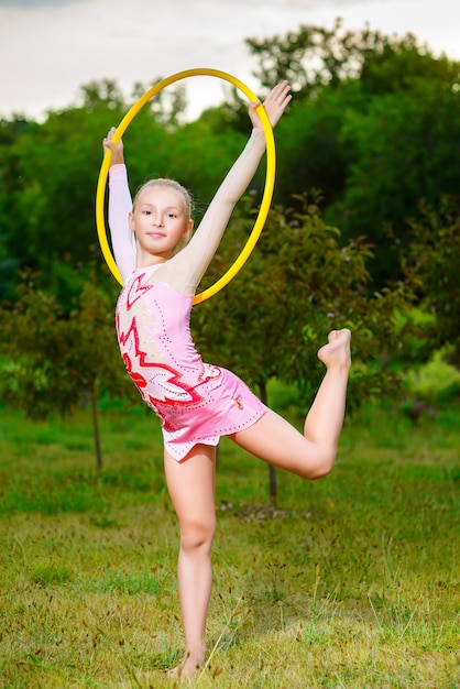 Una niña deportiva haciendo ejercicio con hula hoop sobre el parque