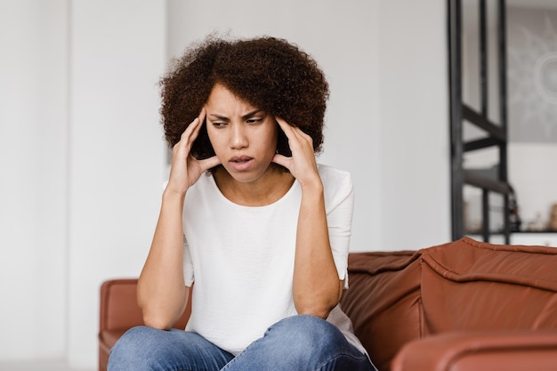 Niña deprimida con migraña Triste mujer afroamericana toca las sienes debido al estrés y la desesperación en su vida Problemas en la vida