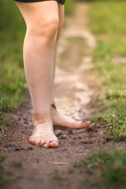 Niña descalza camina a través de charcos de agua después de la lluvia de verano en el campo.