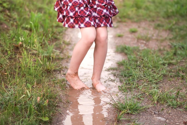 Niña descalza camina a través de charcos de agua después de la lluvia de verano en el campo.