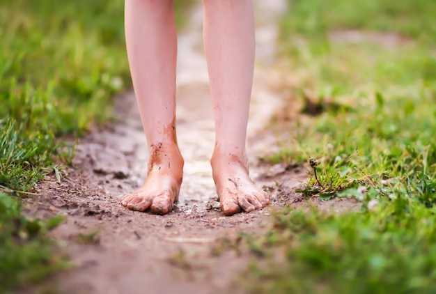 Niña descalza camina a través de charcos de agua después de la lluvia de verano en el campo.