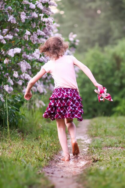 Niña descalza camina a través de charcos de agua después de la lluvia de verano en el campo.