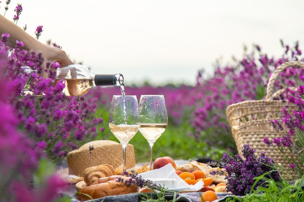 La niña descansa en un campo de lavanda bebiendo vino Enfoque selectivo