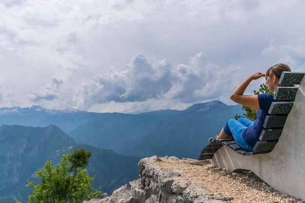 Una niña descansa en la cima de una montaña sentada en un banco inusual