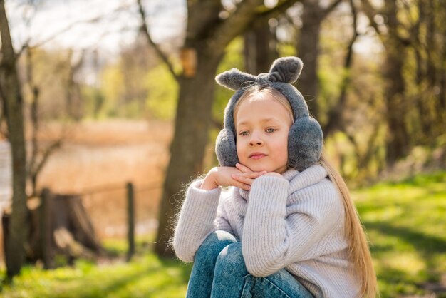 Niña descansando en la naturaleza de primavera Hermosa niña con cabello largo y rubio se sienta en un gran tocón verde b