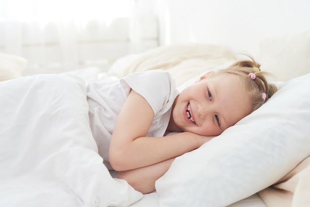 Una niña se despierta por la mañana y sonríe. Dulces sueños.