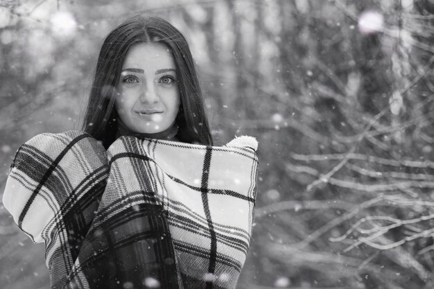 Una niña en un día nublado de invierno de campos y bosques cubiertos de nieve.