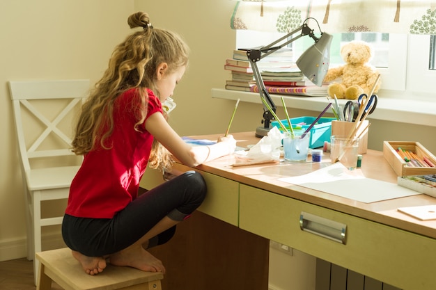 Foto niña dibuja acuarela en la mesa en casa