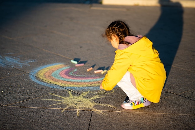 Una niña dibuja un arco iris en los rayos del atardecer.