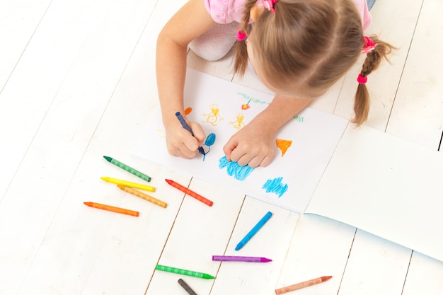 La niña dibuja con crayones en el álbum.