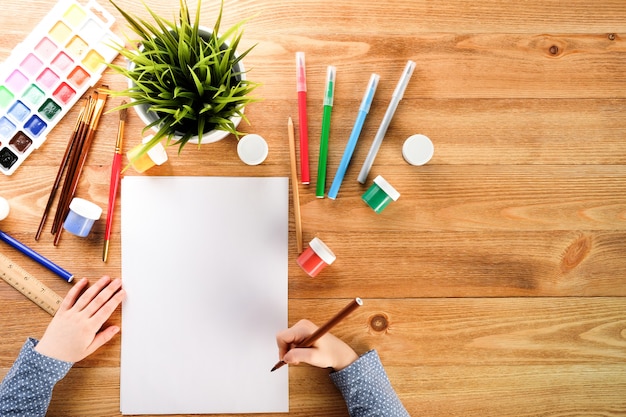 niña dibuja en un cuaderno con pinturas y rotuladores. niño dibuja a la mesa.