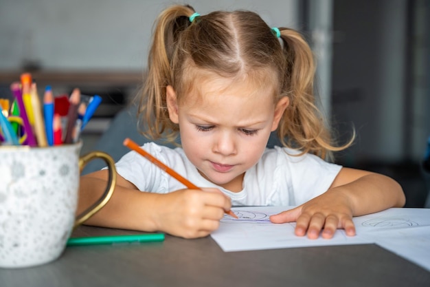 una niña dibuja con lápices de colores en casa