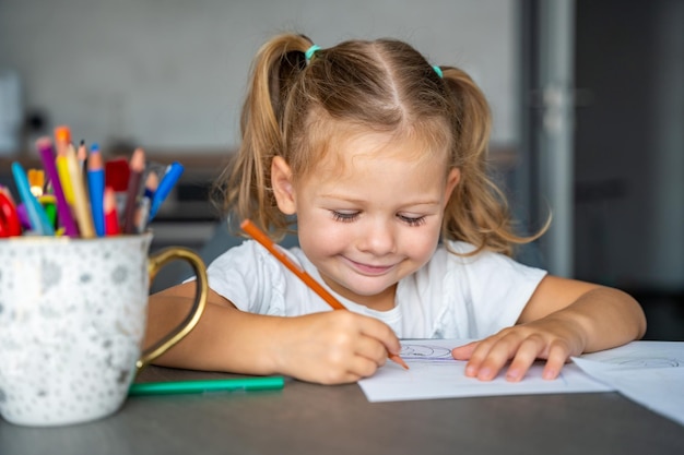 Foto la niña dibuja con lápices de colores en casa.