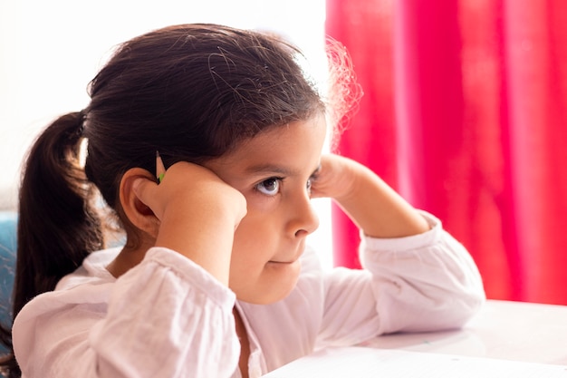 Niña dibuja y pinta en una mesa pequeña