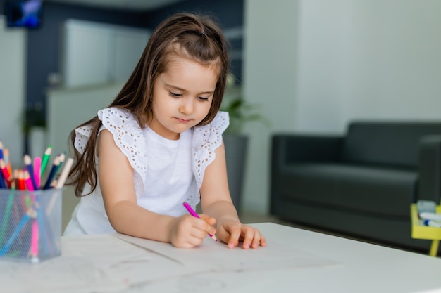 Una niña dibuja sobre una mesa con un dibujo.
