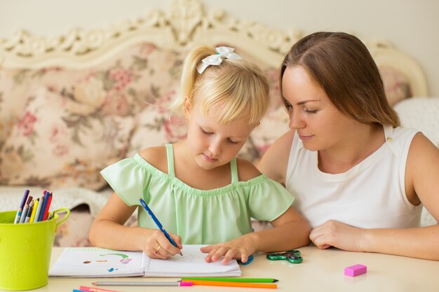 Niña dibujando en casa con la madre