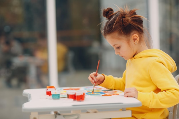 Niña dibujando cuadro de arte pintura con pincel y pinturas de acuarela