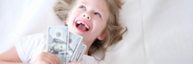 Niña sin dientes frontales sosteniendo dinero en sus manos y sonriendo