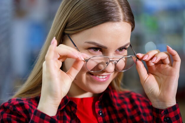 Una niña con discapacidad visual elige gafas. Lleva una camisa y una hermosa sonrisa.