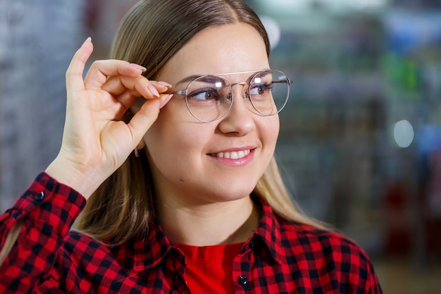 Una niña con discapacidad visual elige gafas. Lleva una camisa y una hermosa sonrisa.