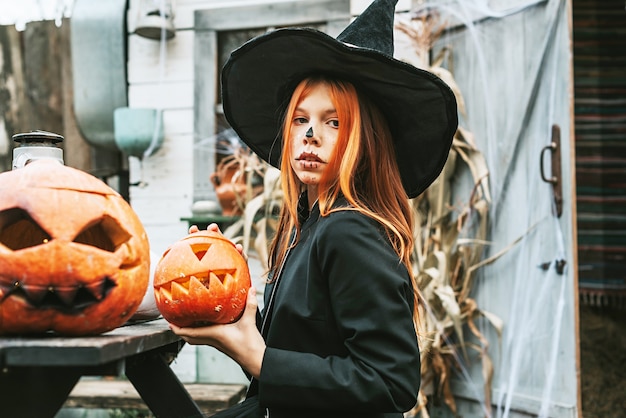 Una niña en un disfraz de bruja divirtiéndose en una fiesta de Halloween en el porche decorado