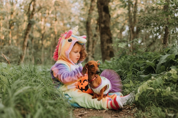 niña con un disfraz de kigurumi de unicornio arcoíris un perro con un vestido con una falda completa espacio para texto