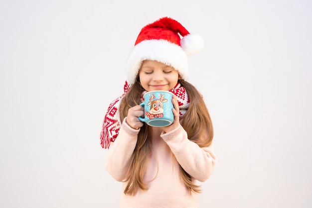 Una niña con un disfraz de Navidad bebe una bebida caliente navideña de una taza.