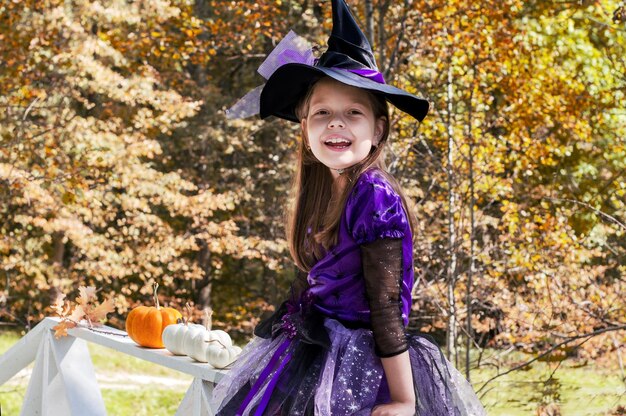 Foto una niña disfrazada de bruja en un parque de otoño.