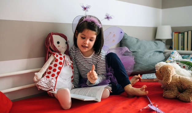 Niña disfrazada leyendo un libro a su muñeca