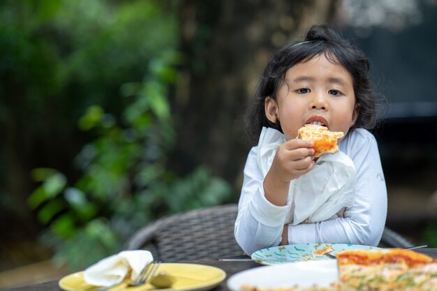 Niña disfruta comiendo pizza al aire libre