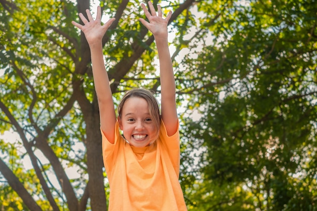 Niña disfruta de la vida, sonríe y levanta las manos